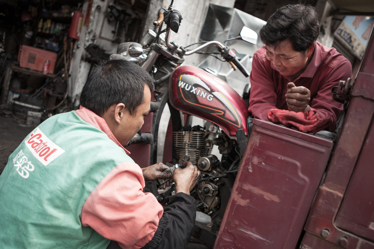 Mechanir repairs motorcycle in China.